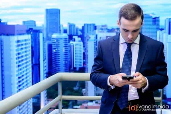 Fotografia de executivo utilizando celular em ambiente corporativo.