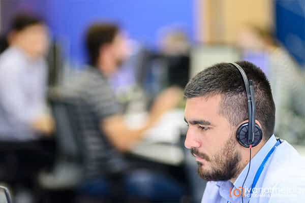 Fotografia de profissional trabalhando com headset e computador.